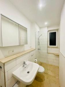 a white bathroom with a sink and a mirror at Exklusives Apartment nahe VW-Halle in Braunschweig
