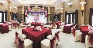 une salle de banquet avec des tables rouges et des chaises blanches dans l'établissement Avila Ketapan Rame Hotel, à Trawas