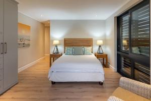 a bedroom with a bed with two tables and two lamps at Hermanus Beach House at CShine in Hermanus