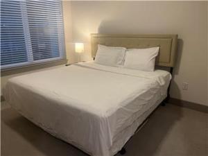 a bedroom with a large bed with white sheets and pillows at Resort-Style Apartments near The Galleria in Houston