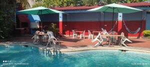 una piscina con mesas, sillas y sombrillas en Poseidon Guest House, en Iquitos