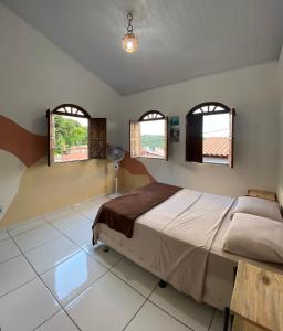 um quarto com uma cama grande e 2 janelas em Terra Hostel e Pousada em Lençóis