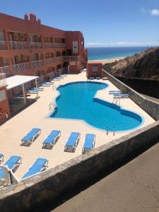 un resort con piscina, sedie e oceano di Beach front apartment with stunning ocean views! a Costa Calma