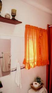 uma casa de banho com uma cortina laranja e um WC em Apartamento en la Romana em La Romana
