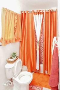 y baño con aseo y cortina de ducha de color naranja. en Apartamento en la Romana, en La Romana