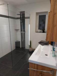 La salle de bains est pourvue d'une douche en verre et d'un lavabo. dans l'établissement Gemütliches Haus mit Zuber, naturnah!, à Weißenborn