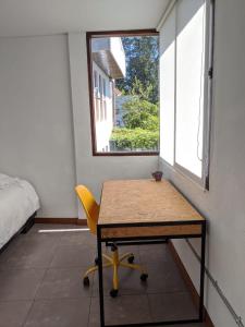 a table and a yellow chair in a room with a window at Play House in Quito