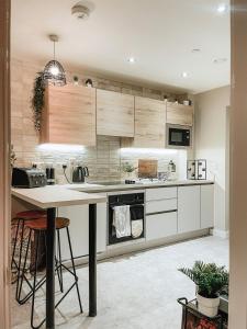 a kitchen with white cabinets and a table with stools at Stylish 1Bed Apartment in Sheffield CC in Sheffield