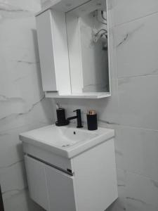 ein weißes Badezimmer mit einem Waschbecken und einem Spiegel in der Unterkunft DarHendou in Nouakchott