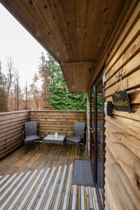 a wooden deck with two chairs and a table at Woodshed Pod in Fort William