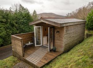 a wooden cabin with a deck on a hill at Woodshed Pod in Fort William