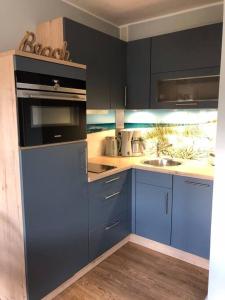 una cocina con armarios azules y fregadero en Maritime Wohnung Ostsee mit privatem Seezugang en Scharbeutz