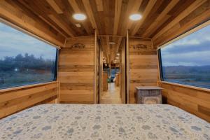 a bedroom with a bed and two large windows at Bus Casa en observatorio de aves in Puerto Montt