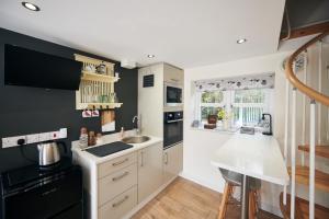a kitchen with white cabinets and black appliances at Carreglwyd in Llandeilo
