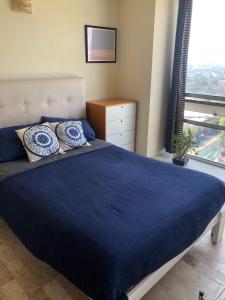 Un dormitorio con una gran cama azul y una ventana en México Querido Jardín, en Ciudad de México