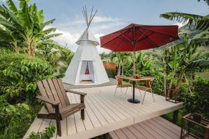 Titiribí的住宿－Cerro Tusa Glamping，木制甲板配有桌子和红色遮阳伞