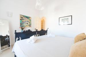 a white bedroom with a bed with two towels on it at Casa Maiorca in Siracusa