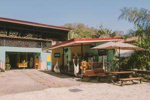a building with a picnic table and umbrellas at Habitat Surf Glamp in Santa Teresa Beach