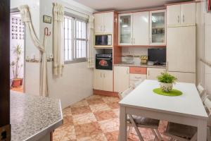 cocina con armarios blancos, mesa y sillas en CASA SALMÓN en Cádiz