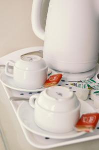 um prato branco com três chávenas e um bule de chá em Gregory by the Warren Collection em Belfast