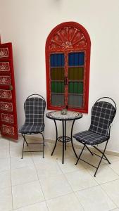 2 Stühle und ein Tisch in einem Zimmer mit Fenster in der Unterkunft Riad Maya in Rabat