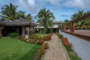 una pasarela frente a una casa con flores en João Praia Hotel, en Maraú