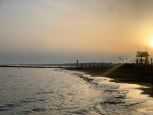 a beach with the sun setting on the horizon at My Dream Home in Nettuno +8 photos