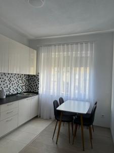 een keuken met een witte tafel en stoelen en een wastafel bij Apartment in Peja city center in Peje