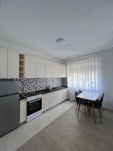 a kitchen with white cabinets and a table and chairs at Apartment in Peja city center in Peje