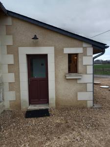 a small house with a red door and a window at Maison a la campagne in Saint-Pierre-de-Chevillé