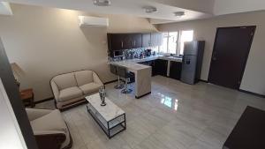 a living room with a couch and a table and a kitchen at Suites Entrelagos in Ciudad Obregón