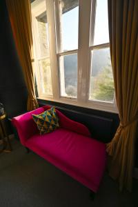 a pink couch in a room with two windows at The Old Vicarage B&B, Corris in Machynlleth