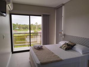 a bedroom with a bed and a large window at Bless in Maragogi