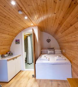 a bed in a small room with a wooden ceiling at Woodside Pod in Fort William