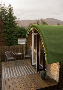 a grass covered deck with a door and chairs at Woodside Pod in Fort William