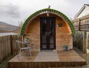 a small wooden cabin with a door and a chair at Woodside Pod in Fort William