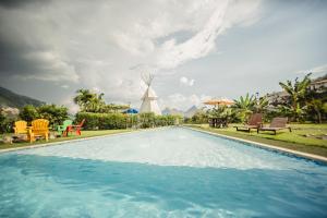 a swimming pool with chairs and a windmill at Cerro Tusa Glamping in Titiribí