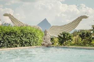 a statue sitting in the water next to a pool at Cerro Tusa Glamping in Titiribí