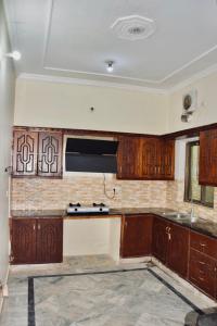 an empty kitchen with wooden cabinets and a sink at Kashee's Lodges in Islamabad