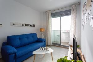 - un canapé bleu dans le salon doté d'une fenêtre dans l'établissement POSEIDON Beach Apartment & parking by Cadiz4Rentals, à Cadix
