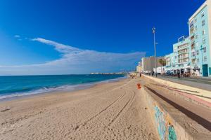 une plage avec des bâtiments et l'océan par beau temps dans l'établissement POSEIDON Beach Apartment & parking by Cadiz4Rentals, à Cadix