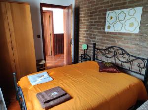 1 dormitorio con 1 cama grande de color naranja y pared de ladrillo en Alojamento local A Giesta en Sao Sebastiao da Giesteira