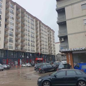 ein Parkplatz mit Autos vor den Gebäuden in der Unterkunft Fush Kosov Apartment Center in Kosovo Polje