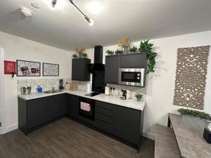 cocina con armarios negros y microondas en Nottage House Premier Apartments, en Cardiff