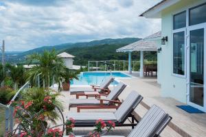 a house with a deck with chairs and a swimming pool at Seascape Villa in Montego Bay