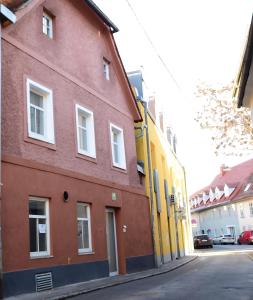 un bâtiment rouge et jaune dans une rue dans l'établissement PM CityAPART Lend, à Graz