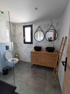 ein Bad mit einem Waschbecken, einem WC und Spiegeln in der Unterkunft Villa Isula Contemporaine Piscine chauffée in Palasca