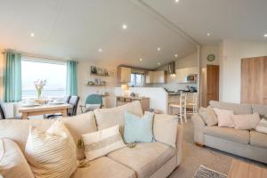 a living room with two couches and a kitchen at Bay View Lodge, Brynowen in Borth
