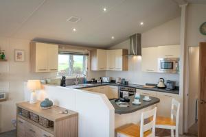 a kitchen with white cabinets and a counter top at Bay View Lodge, Brynowen in Borth