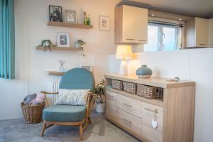 a living room with a chair and a cabinet at Bay View Lodge, Brynowen in Borth